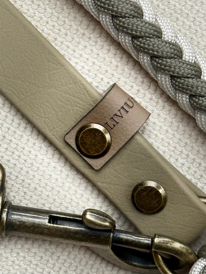 Nahaufnahme Handgefertigte Hundeleine aus Paracord und Biothane in Creamund Olivtönen mit antik-messingfarbenen Karabinern.
